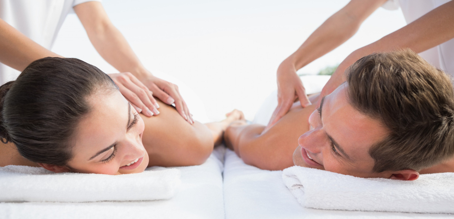 Un cuplu relaxat, care se bucură de un masaj pentru cupluri lângă piscină, în aer liber, la spa